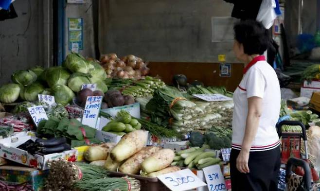 A woman shopping at a traditional market in Seoul checks the price of vegetables on August 20.  Moon Jae-won