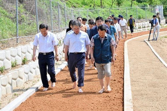 김진열(앞줄 가운데) 대구 군위군수가 지난달 13일 효령면 장군2리 마을 황톳길 준공식에 참석한 뒤 마을 주민들과 맨발 걷기를 하고 있다. 마을 주민들은 올해 군위군으로부터 사업비 2000만원을 지원받아 새마을운동 정신을 바탕으로 한 자조협동사업으로 황톳길을 만들었다. 군위군 제공