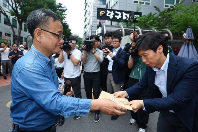 정의정 한국주식투자자연합회(한투연) 대표(왼쪽)가 지난 5월 30일 오후 서울 여의도 더불어민주당 당사 앞에서 열린 금융투자소득세(금투세) 폐지 촉구 집회에 앞서 민주당 관계자에게 성명서를 전달하고 있다.ⓒ연합뉴스