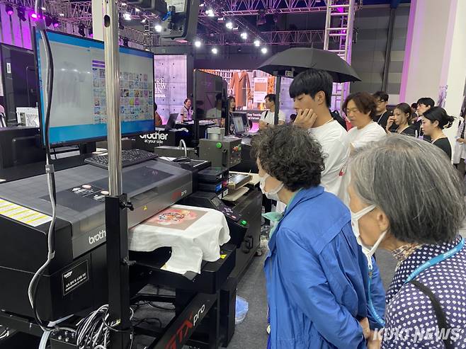 관람객이 AI 기술을 활용한 의류 프린터기를 구경하고 있다. 사진=심하연 기자