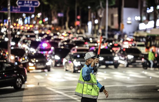 A traffic manager supervise traffic in crowded Daechi-dong, Gangnam District in southern Seoul, at around 10 p.m. in June. [JOONGANG ILBO]