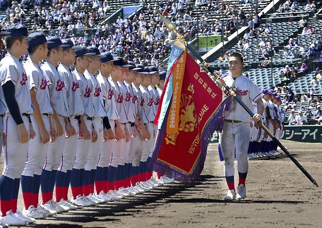 한국계 국제학교인 교토국제고 주장 후지모토 하루키가 23일 일본 효고현 니시노미야 한신고시엔구장에서 열린 전국 고교야구선수권대회(여름 고시엔) 폐회식에서 우승기를 들고 선수들 앞을 걸어가고 있다. 사진 | 연합뉴스
