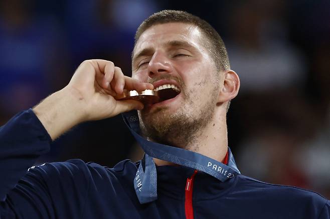 Paris 2024 Olympics - Basketball - Men's Victory Ceremony - Bercy Arena, Paris, France - August 10, 2024. Bronze medallist Nikola Jokic of Serbia bites his medal. REUTERS/Evelyn Hockstein







<저작권자(c) 연합뉴스, 무단 전재-재배포, AI 학습 및 활용 금지>