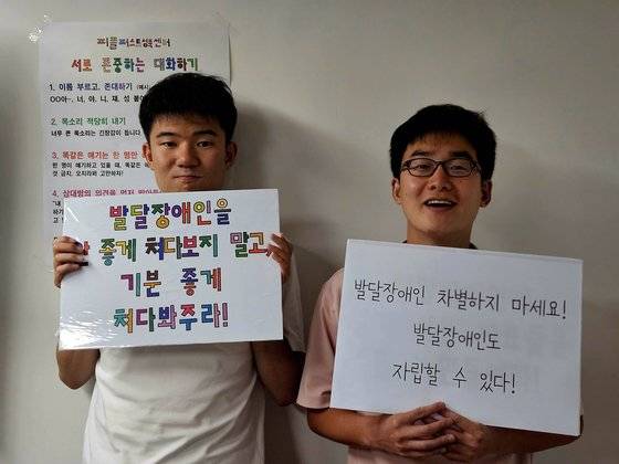 발달장애인 남태준(왼쪽)씨와 이종원씨가 자신의 손글씨를 본뜬 글꼴이 적힌 피켓을 들고 있다. 평소 글씨 쓰기를 좋아하는 두 사람은 기꺼이 자신의 글씨체를 내놓았다. 이영근 기자