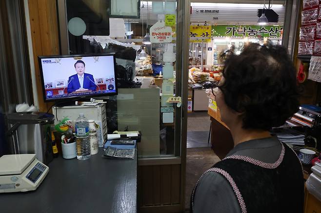 29일 오전 서울 시내 한 전통시장에서 상인이 윤석열 대통령의 국정브리핑 및 기자회견 중계방송을 지켜보고 있다. [연합]