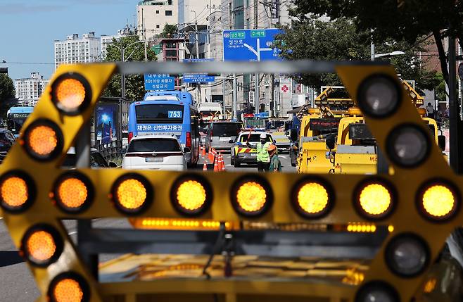 Road authorities control traffic in Yeonhui-dong in Seodaemun District, western Seoul on Friday morning after additional road subsidence was discovered near a sinkhole that appeared a day earlier. [YONHAP]