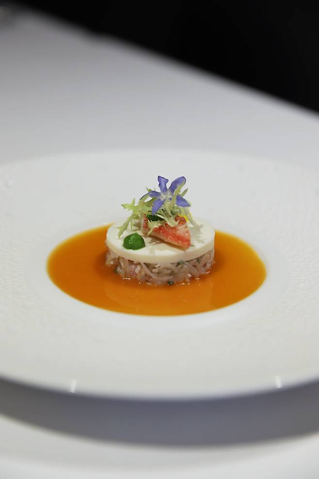 A crab rillettes with cauliflower. The crab dish features expertly seasoned crab meat blended with shallots and chives, crowned with a silky cauliflower puree set in a jelly form. Complemented by tomatoes and various sauces, the delicate seafood flavors are harmoniously balanced and enhanced. /L’Amitié