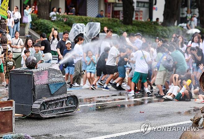 '물싸움 거리극, 알고보니 참여형 연극' (서울=연합뉴스) 서대연 기자 = 서울 한낮 기온이 32도까지 오르며 더운 날씨를 보인 31일 오후 서울 종로구 혜화역 일대에서 열린 '대학로 워터파크 물싸움 거리극' 공연 중 배우가 관객들에게 물을 뿌리고 있다. 2024.8.31 dwise@yna.co.kr