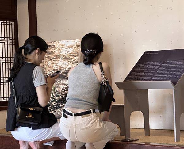 시민이 2층에 전시된 시원한 바다 사진을 감상하고 있다.