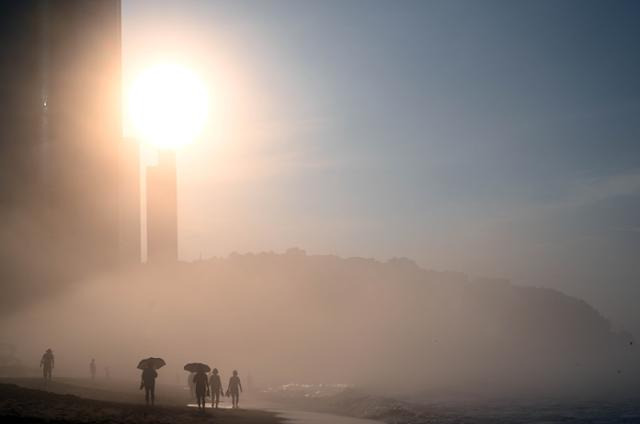 새벽녘, 붉게 타오르는 태양이 부산 해운대 백사장을 뜨겁게 달구기 시작할 무렵, 바다에서 몰려온 해무가 백사장에 낮게 드리우며 몽환적인 풍경을 만들어내고 있다.