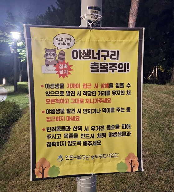 Banner warning of raccoon dog sightings in Songdo Central Park [YONHAP]