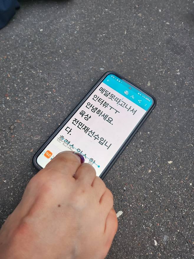 육상 대표팀 전민재가 5일(한국시간) 프랑스 파리 스타드 드 프랑스에서 열린 2024 파리 패럴림픽대회 육상 여자 100m(스포츠 등급 T36) 결선을 마친 후 취재진을 만났다. 스마트폰을 통해 준비한 편지를 보여주고 있다. 사진 | 대한장애인체육회