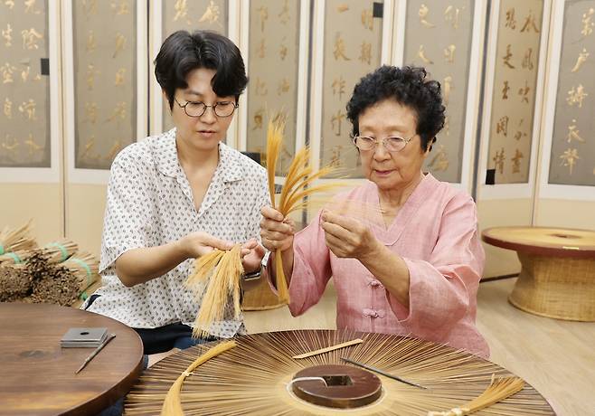 힘들고 고된 양태 일 (제주=연합뉴스) 변지철 기자 = 어머니 장순자(84, 오른쪽) 국가무형유산 갓일·양태 기능보유자와 그의 딸 양금미(48) 이수자가 지난 8월 30일 제주시 조천읍 교래리에 위치한 갓 전시관에서 대나무를 실처럼 가늘게 가공한 대오리를 들어보이며 양태 만드는 작업을 설명하고 있다. 2024.9.8