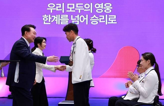 윤석열 대통령과 김건희 여사가 13일 청와대 영빈관에서 열린 '2024 파리 패럴림픽 선수단 격려 오찬'에서 트라이애슬론 김황태 선수와 아내인 경기보조인 김진희 씨에게 각각 국민 감사 메달을 수여 후 악수하고 있다. ⓒ대통령실통신사진기자단