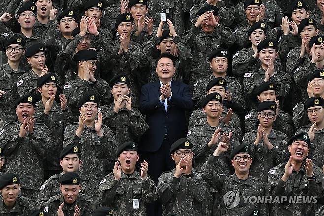 윤석열 대통령, 추석 맞아 강원 최전방 15사단 방문 (서울=연합뉴스) 홍해인 기자 = 윤석열 대통령이 추석인 17일 강원도 최전방 육군 15사단 사령부 사열대에서 사단 장병들과 기념촬영을 마치며 박수를 치고 있다. 윤 대통령 오른쪽 아래는 육군 15사단 군악대에서 복무 중인 방탄소년단(BTS) 리더 김남준(RM) 상병. 2024.9.17 [대통령실 제공. 재판매 및 DB 금지] hihong@yna.co.kr