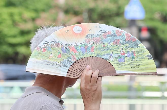 지난달 서울 종로구 광화문광장에서 한 시민이 부채로 뜨거운 햇빛을 가리며 이동하고 있다. 뉴스1