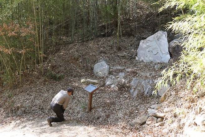 큰 바위에 새겨진 기도처 앞에서 무릎 꿇고 기도하는 형제