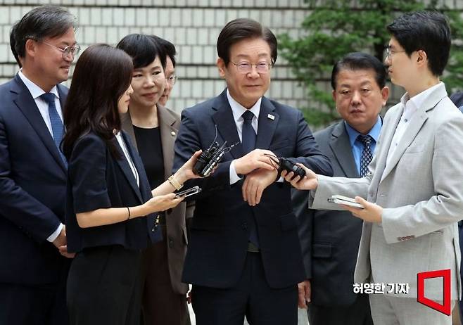 이재명 더불어민주당 대표의 공직선거법 위반 혐의에 대한 결심 공판이 20일 서울 중앙지방법원에서 열렸다. 이 대표가 법원에 도착해 법정에 들어가기 전 시계를 본 뒤 기자들의 질문을 듣고 있다. 뒤에는 민주당 최고귀원과 당직자들이 서 있다. 사진=허영한 기자 younghan@