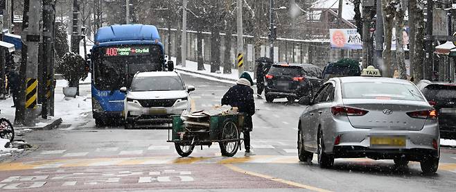 A recycling collector is seen pulling a car along a road in an unrelated file photograph taken in Seoul in 2023. (Im Se-jun/The Korea Herald)