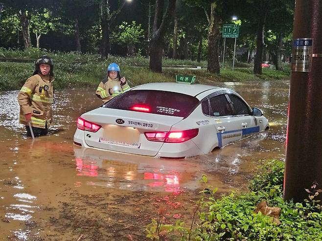 21일 오전 충북 청주시 석소동에서 집중호우로 인해 도로가 침수되어 출동한 소방대원들이 고립된 택시차량을 이동 조치하고 있다. /소방청 제공