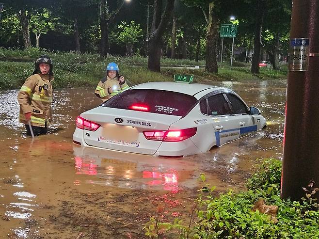 21일 오전 충북 청주시 석소동에서 집중호우로 인해 도로가 침수되어 출동한 소방대원들이 고립된 택시차량을 이동 조치하고 있다. /뉴스1