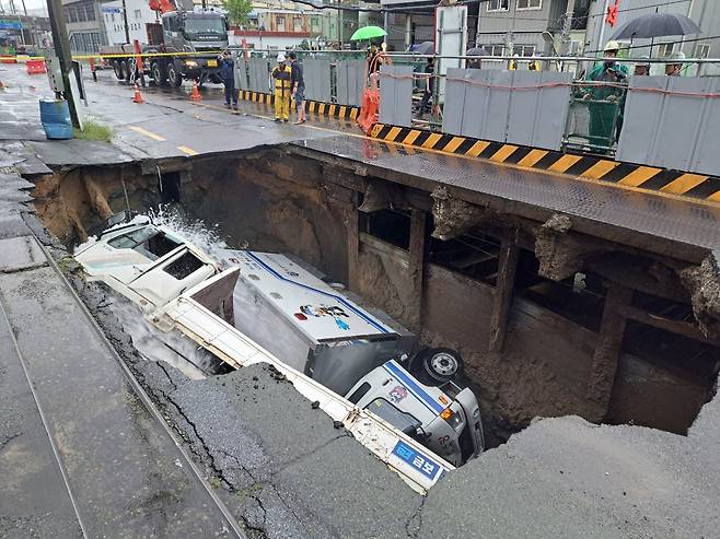 A large sinkhole, approximately 10 meters wide, 5 meters long, and 8 meters deep, opened on a road in Sasang District, Busan, around 8:45 a.m. on Sept. 21, 2024, trapping a firefighting water pump and a 5-ton truck that were providing drainage support./News1