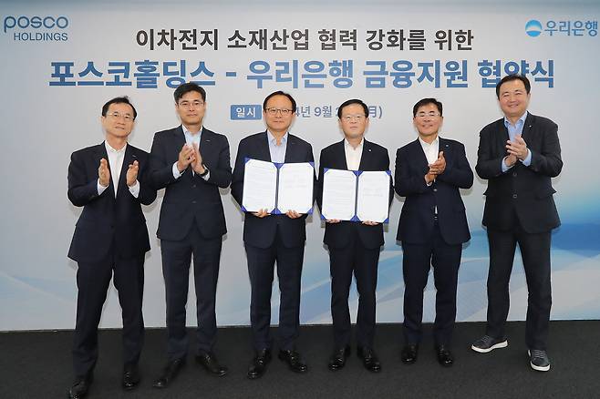 우리은행이 23일 우리은행 본점에서 포스코홀딩스㈜와 ‘이차전지 핵심소재 경쟁력 강화를 위한 금융지원 업무협약’ 을 체결했다. 우리은행 조병규 은행장(오른쪽 세번째), 정기섭 포스코홀딩스 사장(왼쪽 세번째), 우리은행 기동호 기업투자금융부문장(오른쪽 두번째), 김승준 포스코홀딩스 전무(왼쪽 두번째), 김영규 포스코홀딩스 상무(왼쪽 첫번째), 우리은행 정해원 강남기업영업본부장(오른쪽 첫번째)이 함께 기념촬영을 하고 있다. 사진은 우리은행 제공.