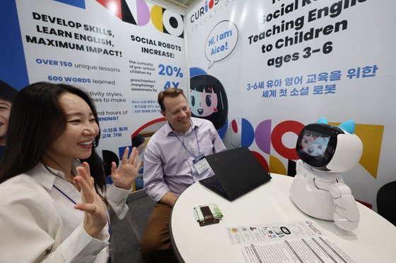 Participants in Edtech Korea Fair 2024 at Coex in southern Seoul demo an English-teaching robot for children on Monday. [YONHAP]