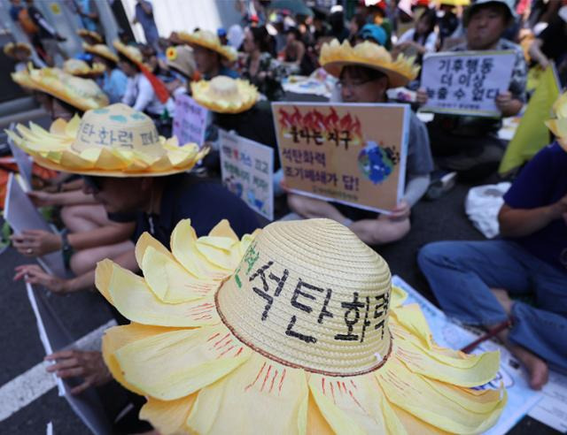 이달 7일 오후 서울 강남대로에서 열린 기후위기 대응 촉구 대규모 집회에서 참가자들이 메시지를 적은 해바라기 모양의 모자를 쓰고 있다. 연합뉴스