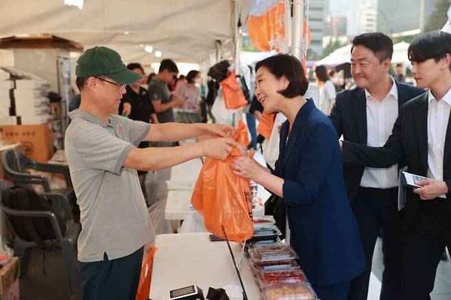 오영주 중소벤처기업부 장관이 서울 종로구 청계광장에서 열린 '동행축제 전통시장 판매전'에서 판매 부스를 둘러보며 제품을 구매하고 있다.(사진=연합뉴스)