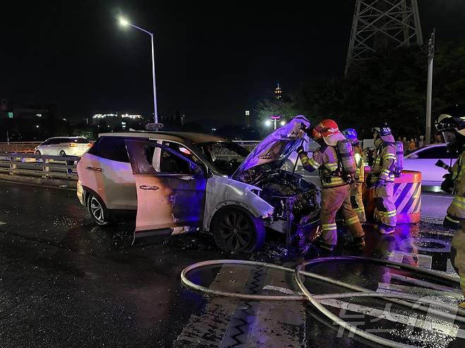 지난 26일 오후 6시 49분쯤 양산시 남부동 7번교차로에서 주행 중이던 싼타페SUV 차량에 불이 나 소방관들이 진화에 나서고 있다.(경남소방본부 제공)