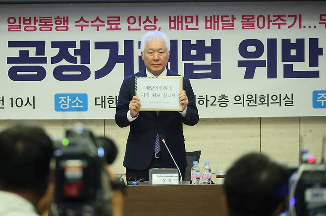 정현식 한국프랜차이즈산업협회 회장이 27일 오전 서울 중구 대한상의에서 한국프랜차이즈산업협회 주최로 열린 \'배달의 민족\' 공정거래법 위반 신고 기자간담회에서 가격 횡포 신고서를 들어 보이고 있다. 연합뉴스