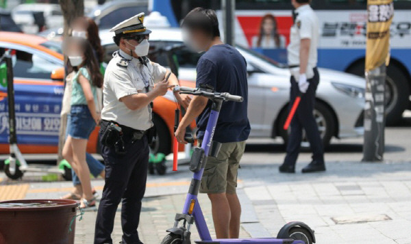 헬멧을 쓰지 않은 전동 킥보드 이용자를 단속하고  있는 경찰.