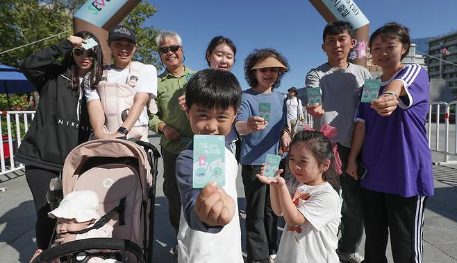 할아버지부터 손주까지 3대가 함께 참가한 양미정씨 가족이 골인 지점인 광화문광장에 모여 웃고 있다. 서울시가 완주자들에게 선물한 기후동행카드를 들었다./고운호 기자