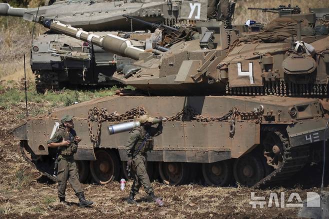 [이스라엘 북부=AP/뉴시스] 지난 27일(현지시각) 이스라엘 북부에서 이스라엘 군인들이 탱크 옆에서 포탄을 옮기는 모습. 이스라엘군은 헤즈볼라와 지상 전에 대비해 북부 국경에 탱크를 집결시키고 예비군을 추가 동원하고 있다. 2024.09.29.