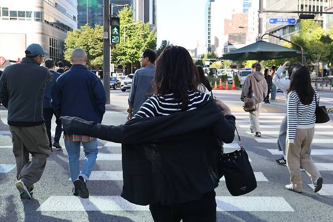 전국 대부분 기온이 뚝 떨어져 올가을 들어 가장 낮은 아침 기온을 기록한 2일 오전 서울 종로구 광화문네거리에서 한 시민이 들고 있던 외투를 입으며 길을 건너고 있다. 김혜윤 기자