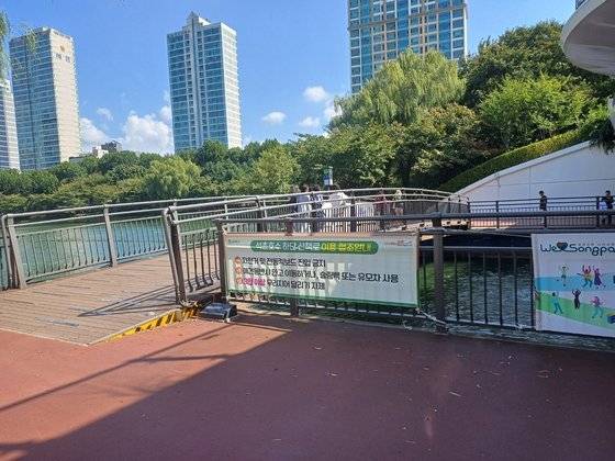 송파구 석촌호수에 붙은 안내 현수막. ″3인 이상 무리지어 달리기 자제″라고 적혀 있다. [송파구청 제공]