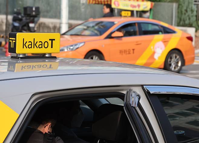 Two Kakao T Blue taxis on the streets of downtown Seoul in November 2023. [YONHAP]