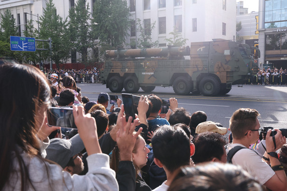 People take photos as a military parade featuring Hyunmoo missiles passes through Gwanghwamun in downtown Seoul Tuesday. [YONHAP]