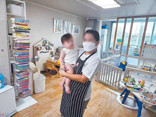 A Filipino caregiver holds a baby at a home in Seoul in September. [SEOUL METROPOLITAN GOVERNMENT]