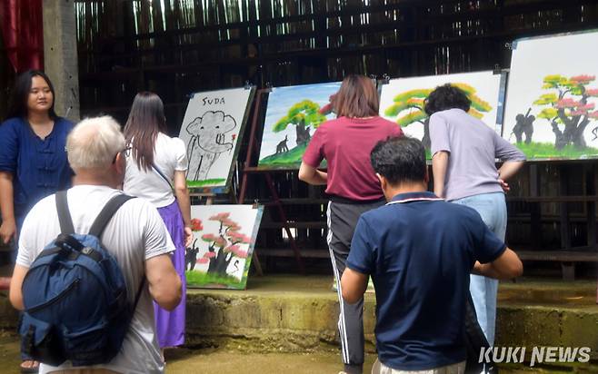 코끼리화가 그림이 완성되고 전시장에 그림이 놓여지자 관광객들이 구매를 위해 그림을 자세히 살피고 있다.