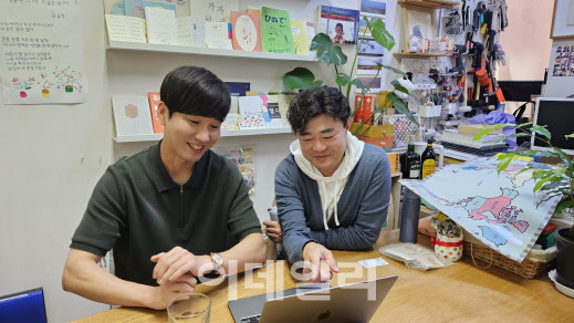 4일 오후 서울 동대문구의 푸른사람들 사무실에서 김성일(왼쪽)씨와 문종석씨가 어머니학교 학생들의 활동사진을 보며 미소 짓고 있다. (사진=김세연기자)