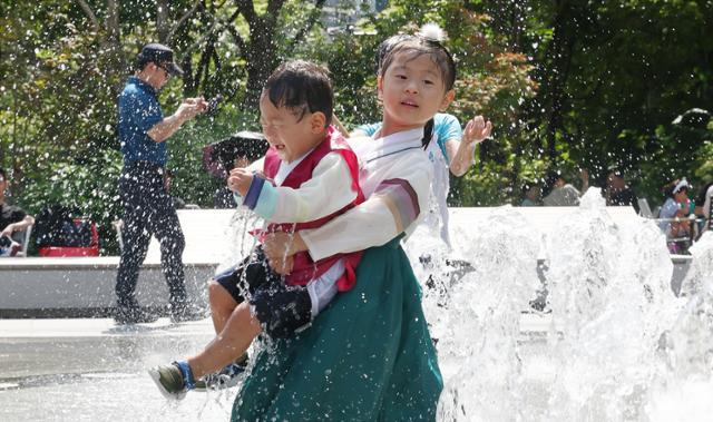 추석 연휴였던 지난달 16일 서울 종로구 광화문광장 바닥분수대에서 한복을 입은 어린이들이 무더위를 피해 시원한 시간을 보내고 있다. 연합뉴스