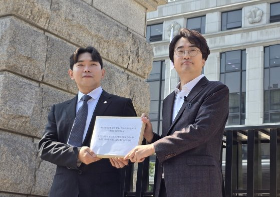 한국게임이용자협회장 이철우 변호사(왼쪽)와 유튜버 김성회씨가 8일 서울 종로구 헌법재판소 앞에서 헌법소원 심판 청구서를 들고 있다. 연합뉴스