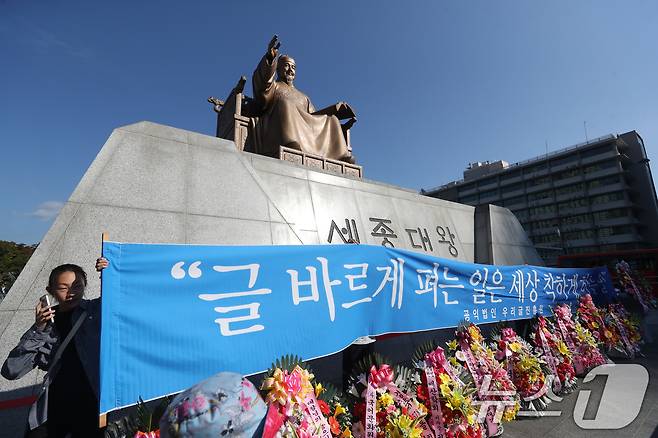 한글날 578돌인 9일 오전 서울 세종대로 광화문광장 세종대왕 동상 앞에서 우리글진흥원 관계자들이 현수막을 펼치고 있다. 2024.10.9/뉴스1 ⓒ News1 이승배 기자