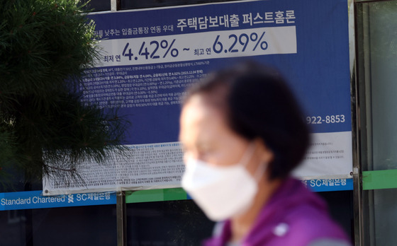 A woman passes a loan promotion poster at a bank in Seoul on Wednesday. [NEWS1]