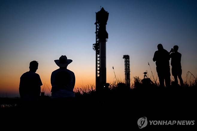 12일(현지시간) 미국 텍사스주 보카 치카 인근 발사대에 놓인 스페이스X 스타십을 바라보는 방문객들.  [AFP 연합뉴스]