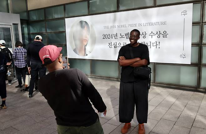 주말인 13일 오전 교보문고 광화문점 한강 노벨문학상 축하 현수막 앞에서 외국인들이 기념촬영을 하고 있다(사진=연합뉴스).