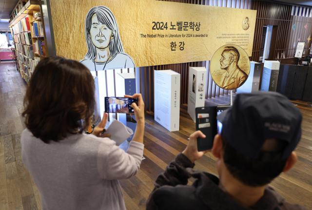 시민들이 15일 서울 종로구 교보문고 광화문점에서 노벨문학상을 수상한 한강 작가의 책 코너를 사진에 담고 있다. 연합뉴스