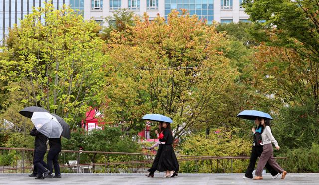 가을비가 내린 18일 오전 서울 광화문광장에서 우산을 쓴 시민들이 발걸음을 옮기고 있다. 뉴스1